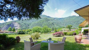 An outdoor seating area with wicker chairs and a table, surrounded by potted plants and a view of a mountainous landscape. - Stunning home in Camaiore with WiFi (Camaiore)