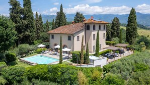 A two-story villa with a swimming pool, outdoor seating, and a view of the mountains. - Lovely home in Terranuova Bracciolini (Terranuova Bracciolini)