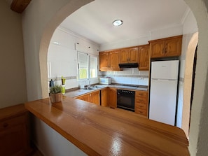 A kitchen with wooden cabinets, a stainless steel sink, a white refrigerator, and a built-in oven.