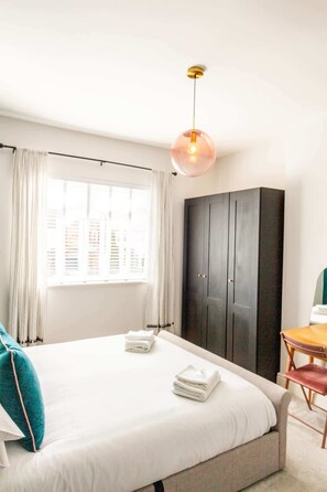 A hotel room with a bed, a wardrobe, a desk, and a hanging light fixture. - Charming Getaway: 3BR Home in the Heart of Chester (Chester)