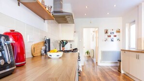 Une cuisine moderne avec des plans de travail en bois, une bouilloire rouge, une cuisinière et un dosseret de carrelage blanc.