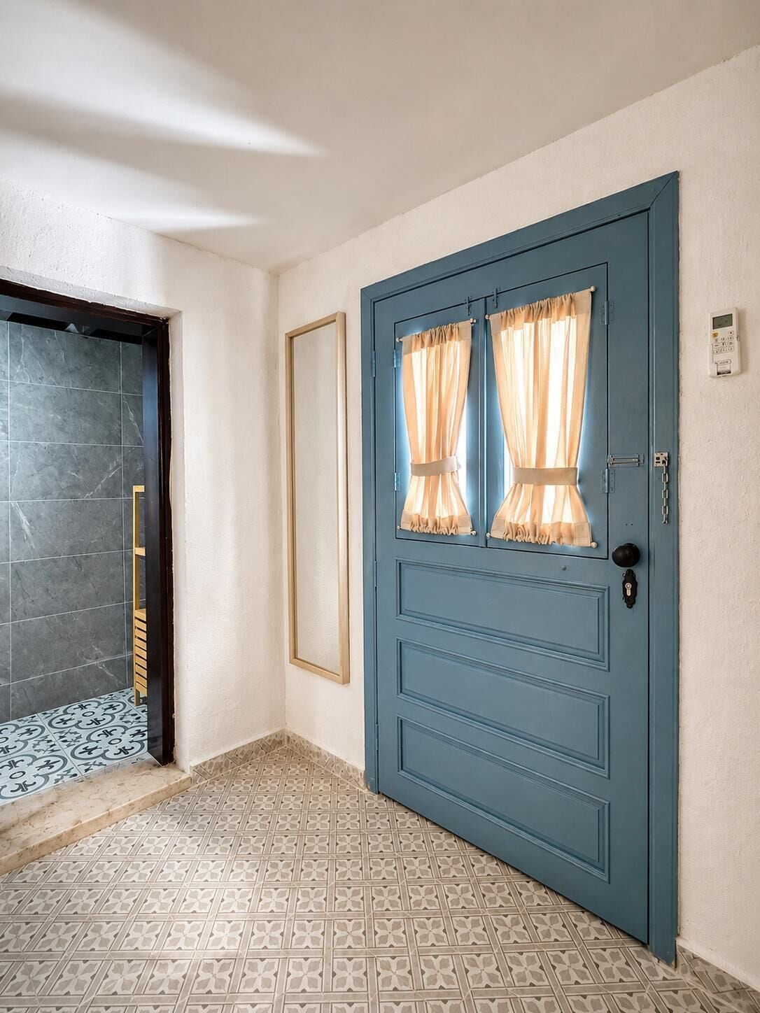 A blue door with a window, a tiled floor, and a wall-mounted device.