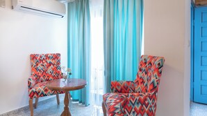 Een kamer met twee kamerstoelen met een patroon, een klein rond tafeltje en een blauwe deur.