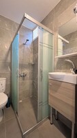 Un baño moderno con cabina de ducha de vidrio, lavamanos y retrete.