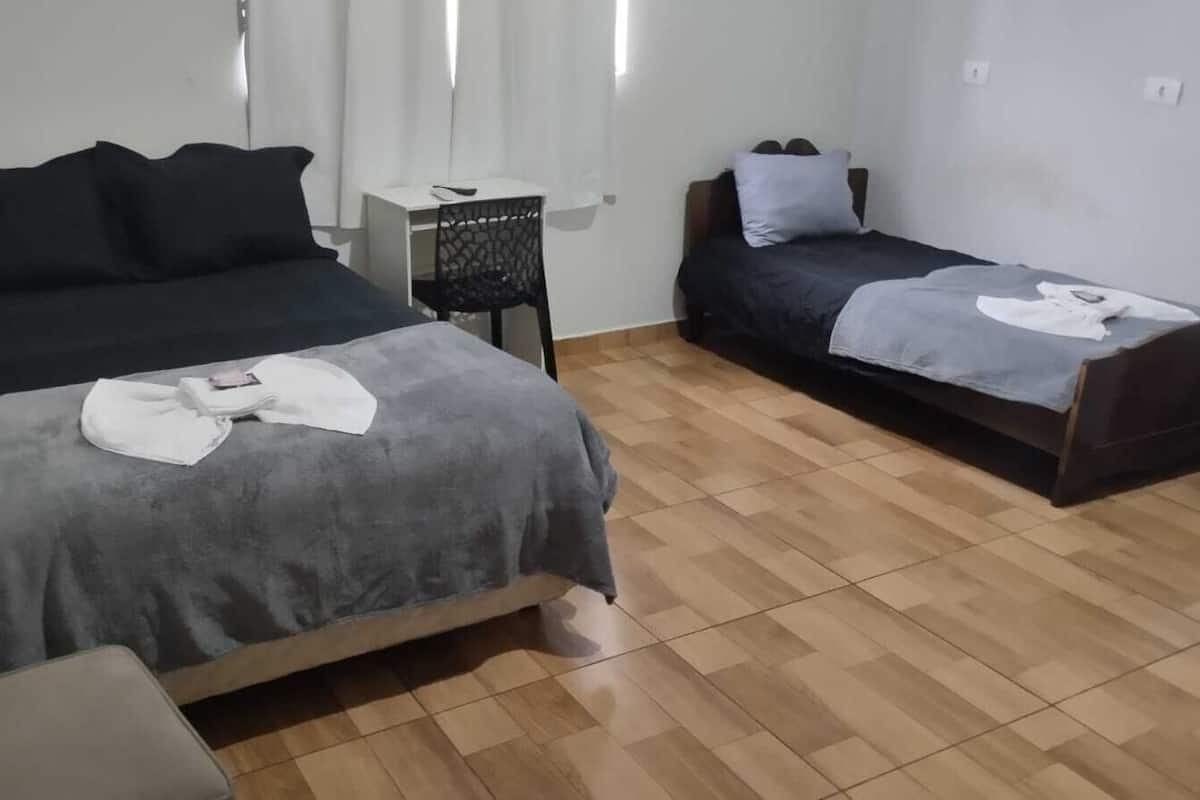 A room with two beds, a small table, and a chair.