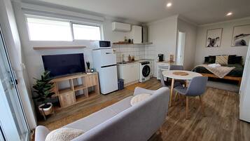 A compact living space with a kitchenette, a sofa, a dining table, and a TV.