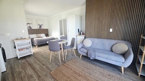 Una sala moderna con un sofá gris, una mesa de comedor y una zona de cocina.