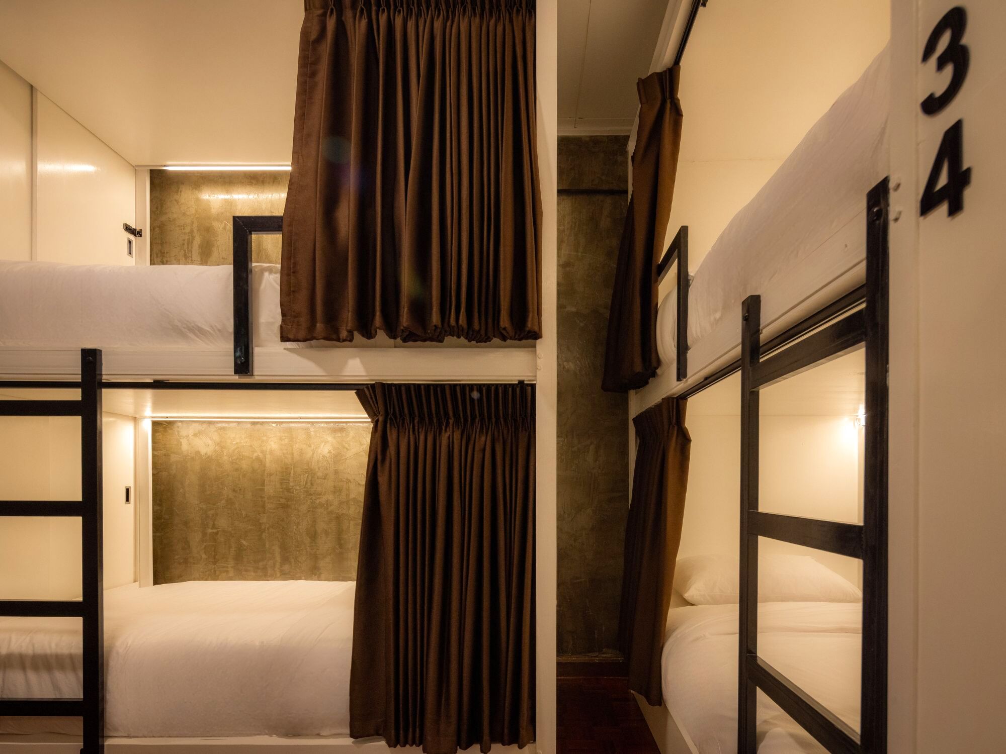 Un dormitorio con literas, cortinas y el número 34 en la pared.