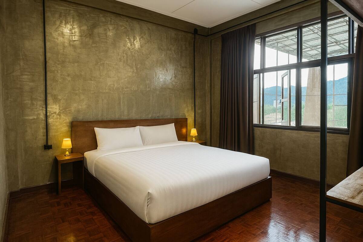 A hotel room with a large bed, wooden headboard, two bedside lamps, and a window with a view of the outdoors.