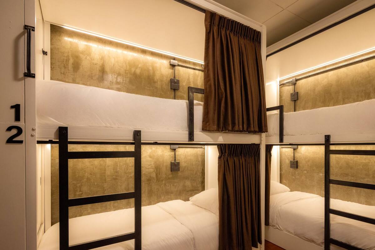 A bunk bed room with two beds, each with a headboard and a curtain.