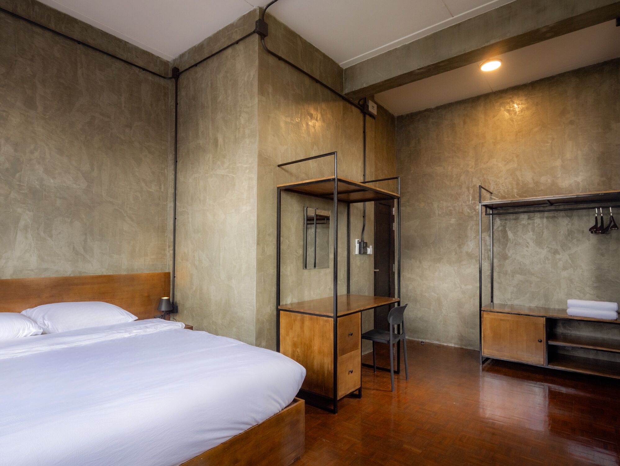 Una habitación de hotel moderna con una cama grande, un escritorio de madera, un espejo y un armario.