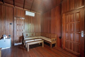 A wooden room with a bench, a small table, and a door. - Wood Village Nusa Dua Bali (Kutuh)