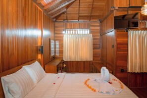 A wooden room with a bed, a desk, and a window with curtains. - Wood Village Nusa Dua Bali (Kutuh)