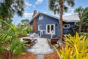 A house with a blue exterior, a brick chimney, and a front porch with white railings.