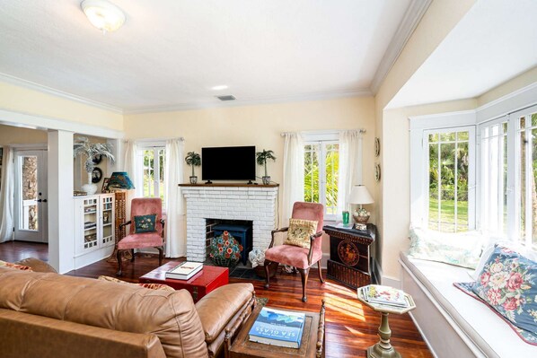A spacious living room with a fireplace, leather sofa, and a television mounted above it.