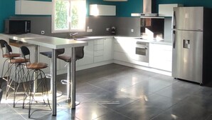 Una cocina moderna con una isla central, electrodomésticos de acero inoxidable y paredes color aguamarina.