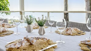 A table set for a meal with plates, cutlery, and glasses, decorated with woven placemats and small potted plants. - Sunset Cottage on the Burrum River (Burrum Heads)