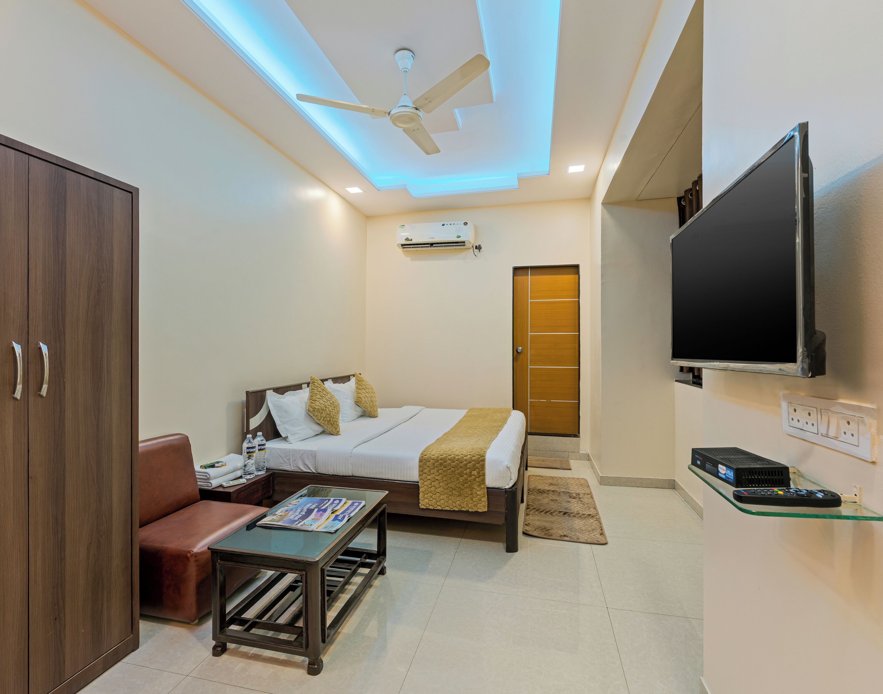 A hotel room with a bed, a desk, a TV, and a wardrobe.