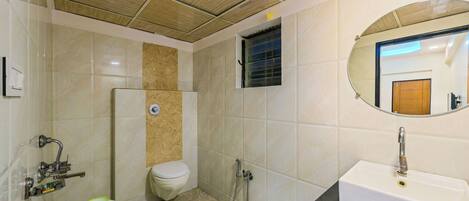 A bathroom with a toilet, shower, sink, and a mirror.