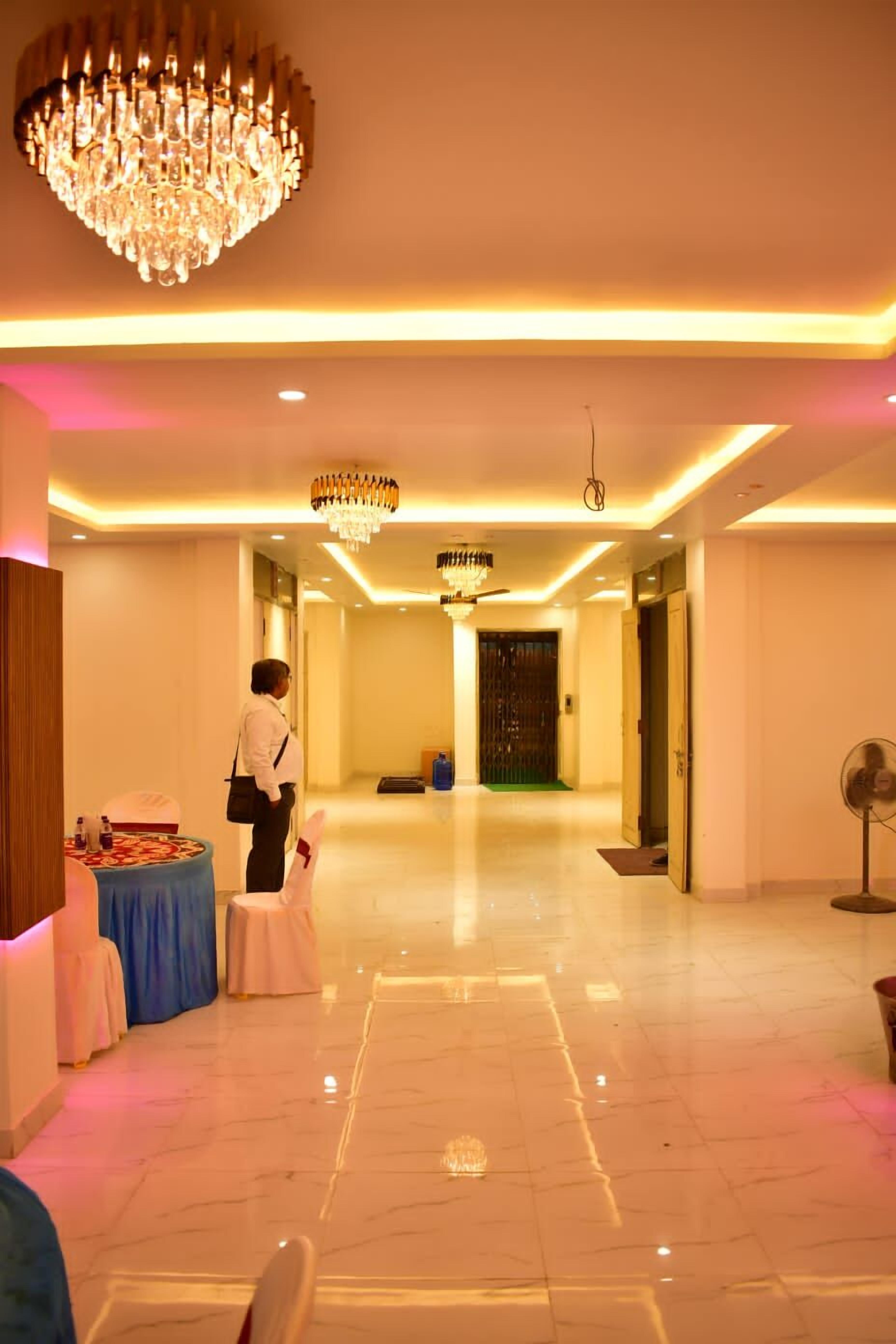 Un hall d’hôtel avec un lustre, un comptoir d’accueil et une table recouverte d’une nappe bleue.