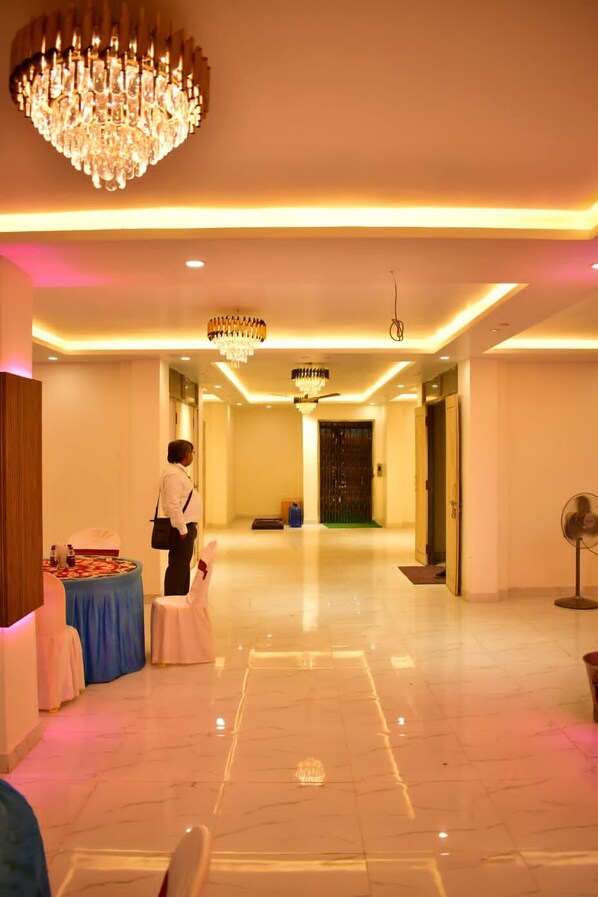 A hotel lobby with a chandelier, a reception desk, and a table with a blue tablecloth. - Sagar Luminoire Hotel (Patna)