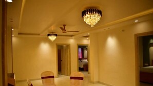 A hotel corridor with chandeliers, a ceiling fan, and a room visible in the background. - Sagar Luminoire Hotel (Patna)