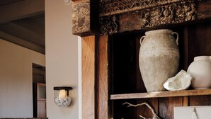 A rustic interior with a wooden shelf displaying pottery and a stone vase. - Sedona Infinity Pool Paradise | Red Rock Views | Hot Tub (Sedona)