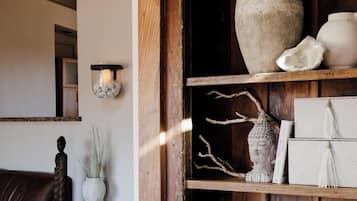 A rustic interior with a wooden shelf displaying pottery and a stone vase.