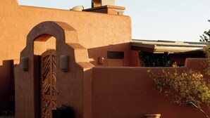 A building with a stucco exterior, a large arched entrance, and a small garden with cacti and rocks. - Sedona Infinity Pool Paradise | Red Rock Views | Hot Tub (Sedona)