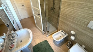 Een badkamer met een groot bad, een douchecabine, een bidet en een toilet.