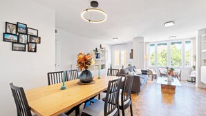 A spacious dining area with a wooden table and chairs, a vase with flowers, and a modern pendant light.