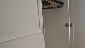 A white wardrobe with a mirrored door, a hanging rod, and a small drawer.
