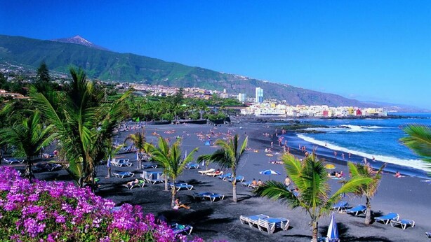A beach with lounge chairs and umbrellas, a mountain in the background, and a coastal town. - Fantastico 4, center Puerto de la Cruz, terrace, air conditioning, free parking (Puerto de la Cruz)