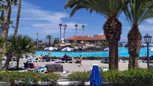 A resort with a pool area, palm trees, and a building with a red roof. - Fantastico 4, center Puerto de la Cruz, terrace, air conditioning, free parking (Puerto de la Cruz)
