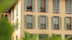 A building with multiple windows, some with shutters, and balconies with flowers. - Casa MAMMA, family relaxation on Lake Iseo - elegant apartment - 2 rooms (Lovere)