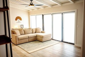 A living room with a beige sectional sofa, a ceiling fan, and large sliding glass doors.