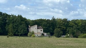 A rural house with a large field in front, surrounded by dense forest. - 5 Bedroom Villa in Montcuq en quercy (Montcuq en quercy)