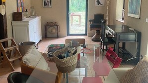 A spacious living room with a glass coffee table, a fireplace, and a view through a glass door to an outdoor area. - 5 Bedroom Villa in Montcuq en quercy (Montcuq en quercy)