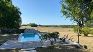 A swimming pool with a stone structure, surrounded by a paved area with chairs and a tree. - 5 Bedroom Villa in Montcuq en quercy (Montcuq en quercy)