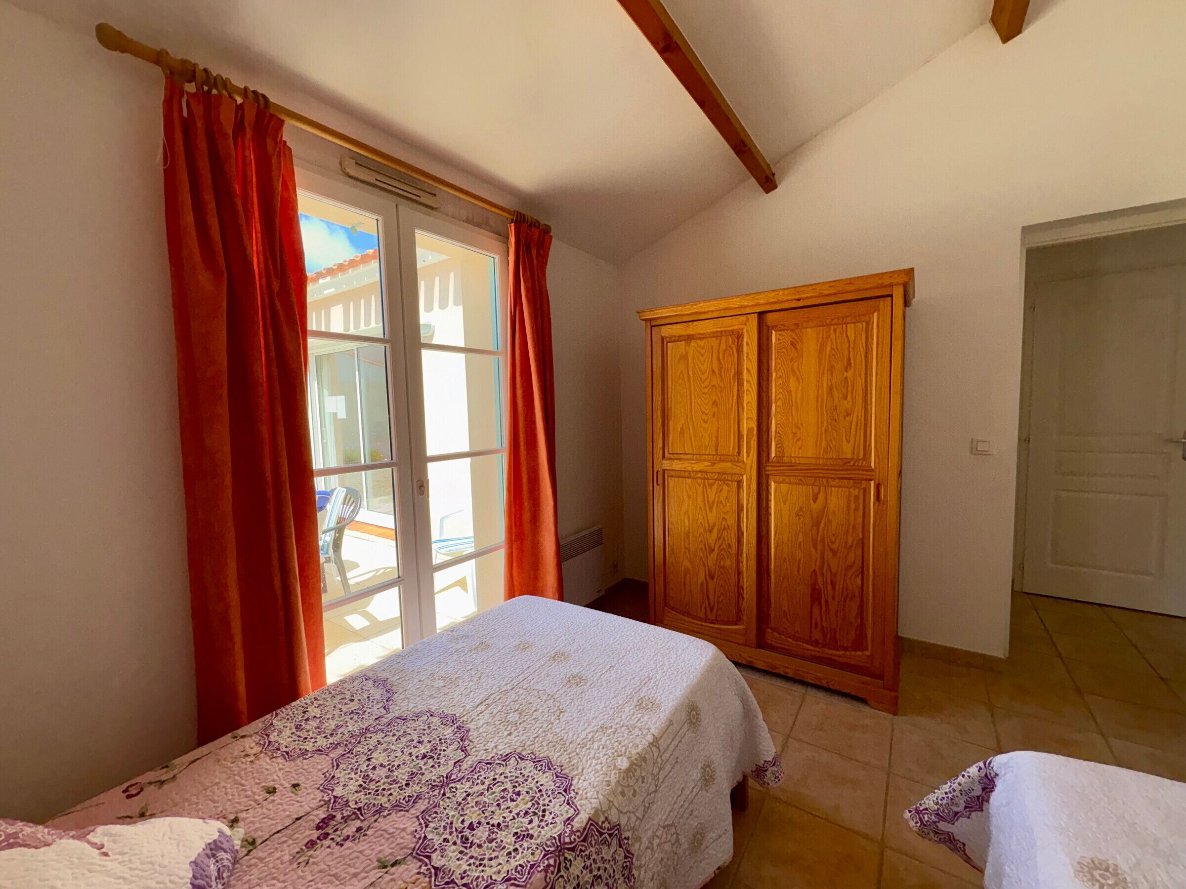 Ein Schlafzimmer mit Bett, Schrank und einem Fenster mit Vorhängen.
