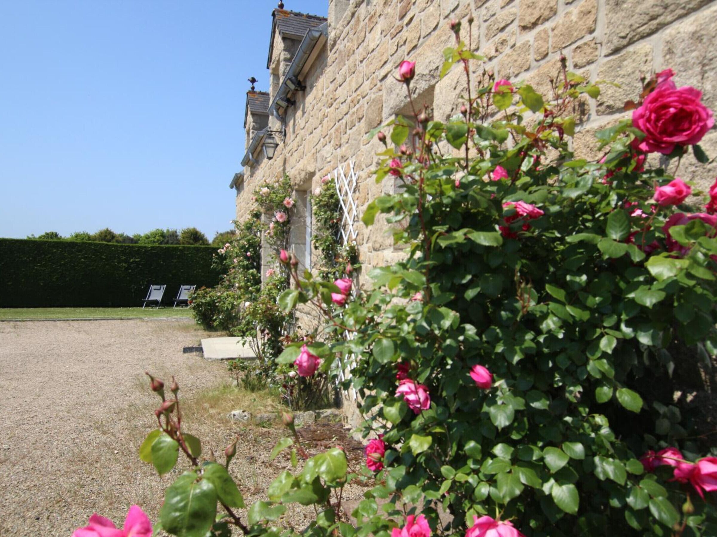 A stone building with a gravel driveway and a rose garden.