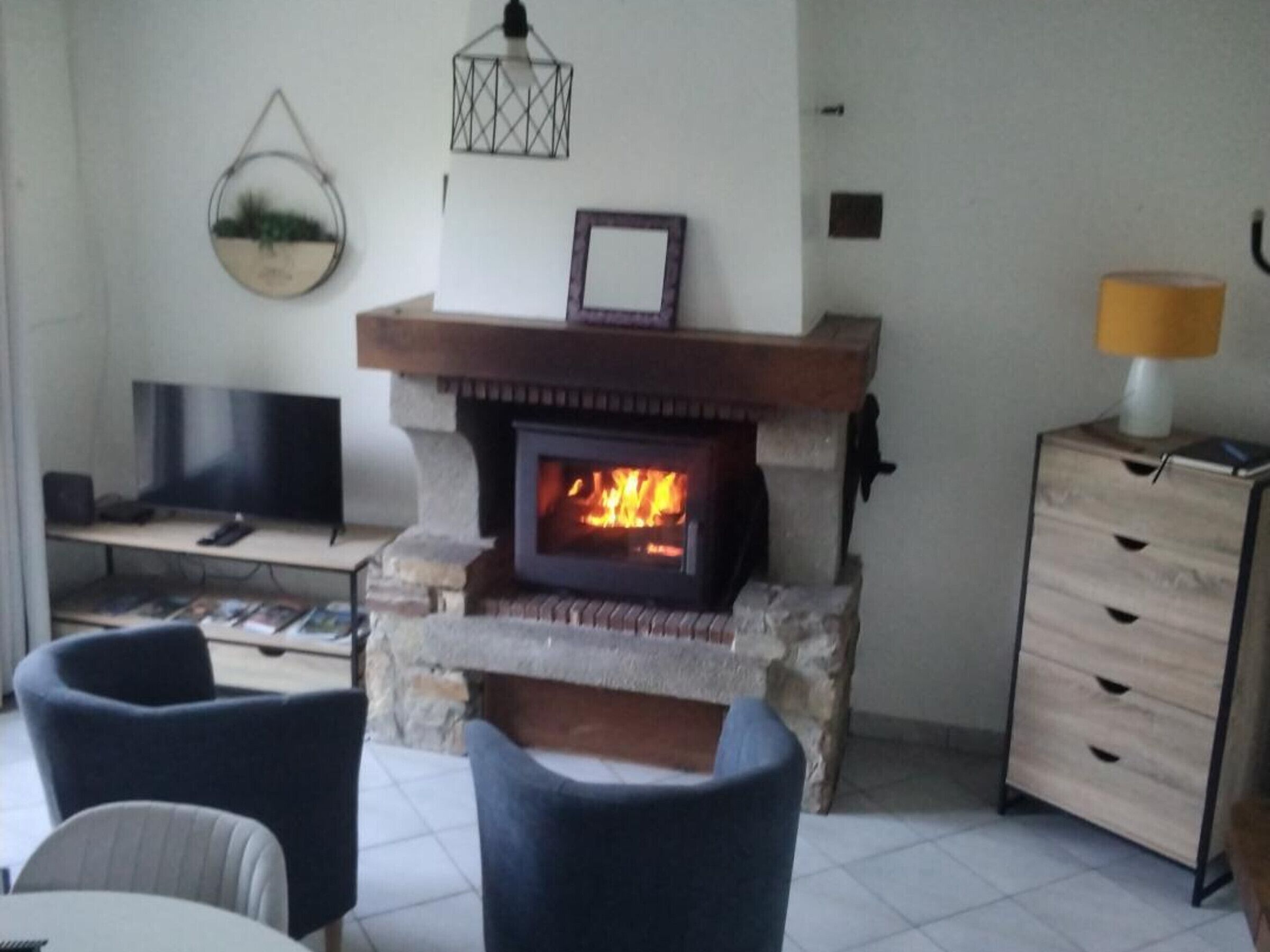 Ein Wohnzimmer mit Kamin aus Stein, einem Fernseher und einer Lampe.