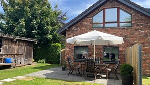 A brick house with a patio, a wooden shed, and a large tree. - Modern vacation home that leaves nothing to be desired at the Eifel National Park (Hürtgenwald)