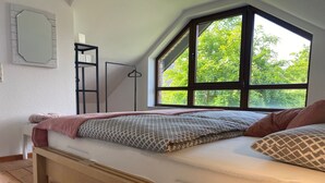 A bedroom with a loft bed, a window with a view of greenery, a wooden floor, and a white wall. - Modern vacation home that leaves nothing to be desired at the Eifel National Park (Hürtgenwald)