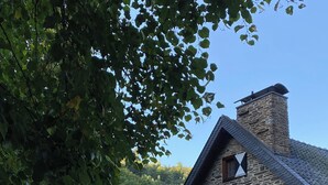 A stone building with a stone chimney, a window with a triangular awning, and a stone wall. - Modern vacation home that leaves nothing to be desired at the Eifel National Park (Hürtgenwald)