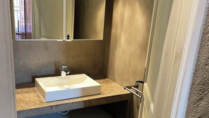 A bathroom with a white sink, a mirror above it, and a green bath mat on the floor. - Gite in superb stone farmhouse in idyllic setting, 10 minutes from beaches. (Le Castellet)