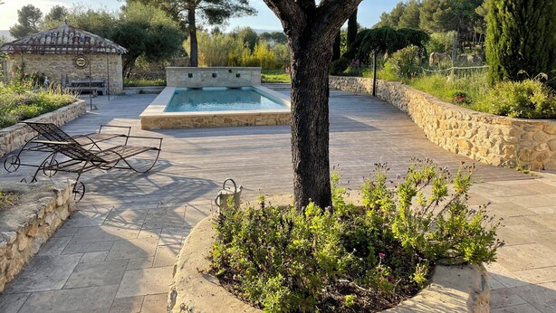 A pool area with stone walls, a pergola, and a stone building in the background. - Gite in superb stone farmhouse in idyllic setting, 10 minutes from beaches. (Le Castellet)