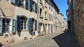 Eine enge Kopfsteinpflasterstraße, gesäumt von historischen Gebäuden mit Steinfassaden und blauen Fensterläden.