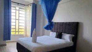 A bedroom with a bed, curtains, a headboard, a ceiling light fixture, and a window. - Lux Suites Naxity Apartments Nakuru (Nakuru)