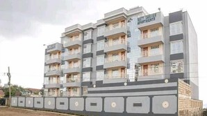 A multi-story building with balconies, labeled "DAVID CAESUEN APARTMENTS." - Lux Suites Naxity Apartments Nakuru (Nakuru)